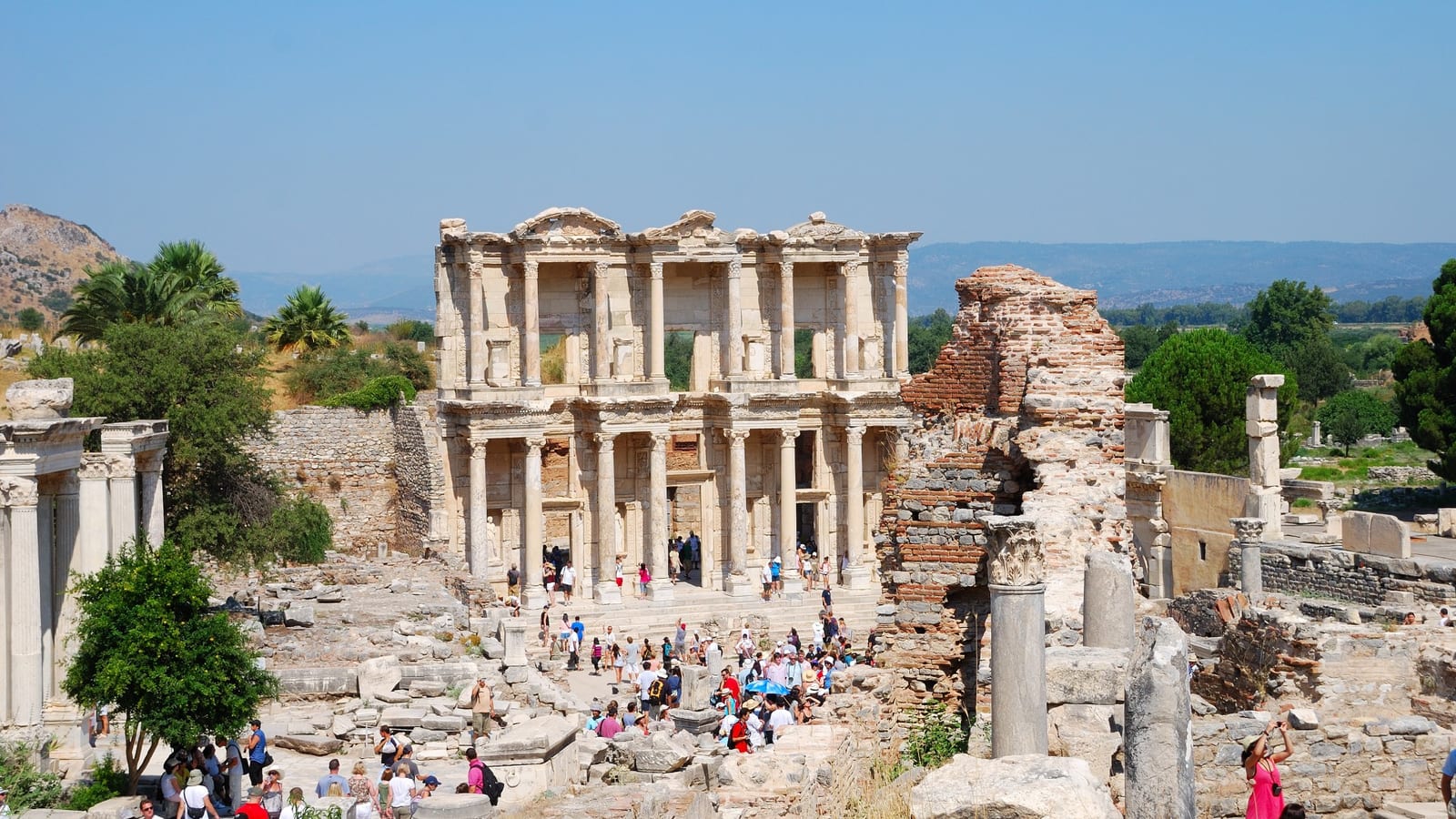Summer visitors gathered in front of the Library of Celsus at Ephesus under a hot midday sun