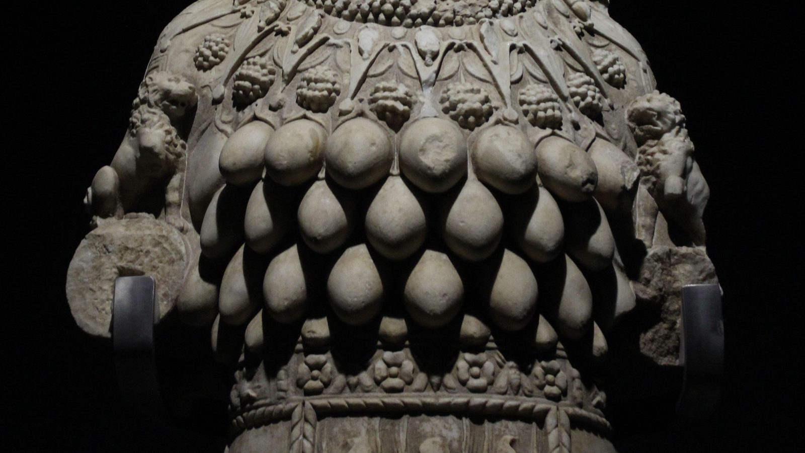 The chest of the Great Artemis statue in the Ephesus Museum, Selcuk: rows of smooth oval shapes without nipples below a band of carved clusters, with small lions on her arms