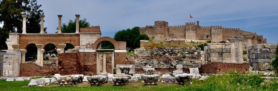 Arches and columns of the Basilica of St. John with the walls and towers of Selcuk fortress behind