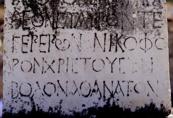 Weathered white marble at Ephesus carved with Greek capital letters, including a round phi and the word for Christ
