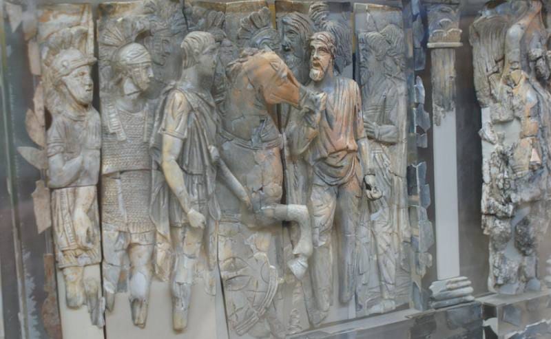 Carved ivory relief frieze of Roman figures in military dress displayed behind glass