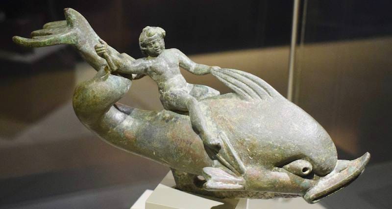 Bronze statuette of Eros riding a dolphin displayed in a case at the Ephesus Museum