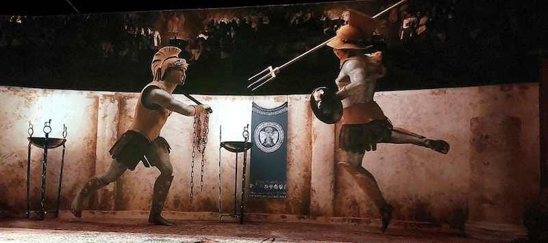 Two projected gladiators, one with a sword and one with a trident, facing off on a curved arena wall.