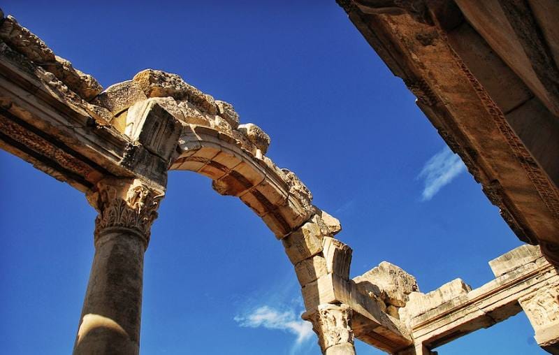 Low-angle view of the Roman arch of the Temple of Hadrian resting on a carved Corinthian column