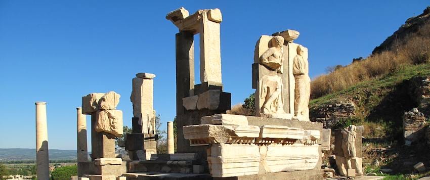 The Memmius Monument in Ephesus, its marble piers and carved figures standing against a clear blue sky.