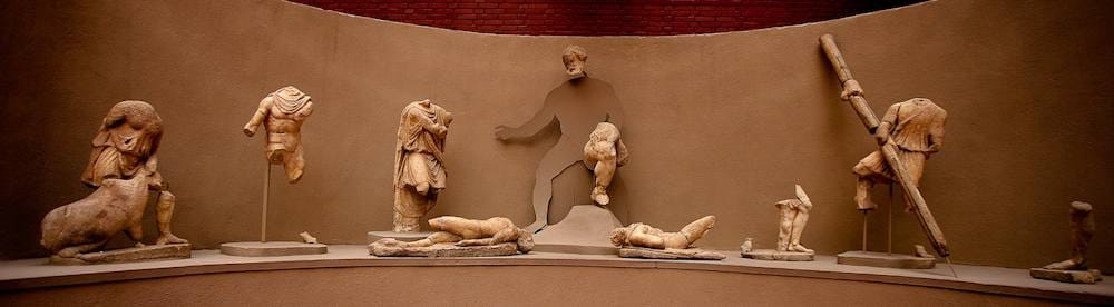 Marble figures of the Polyphemus statue group arranged in a curved niche at the Ephesus Archaeological Museum.