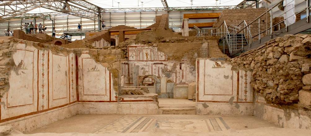 Roman room at the Ephesus Terrace Houses with red-paneled wall frescoes and a geometric mosaic floor.